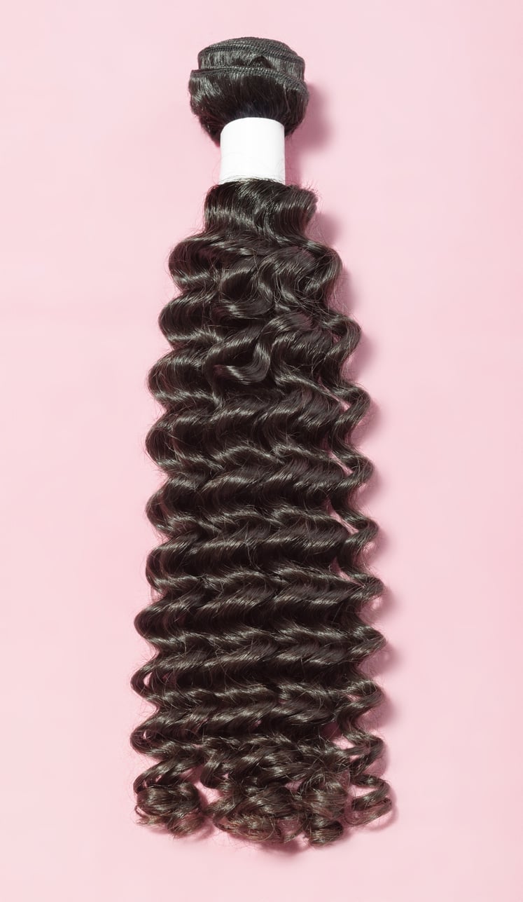 Deep curly black human hair weaves extensions bundles upon pink background